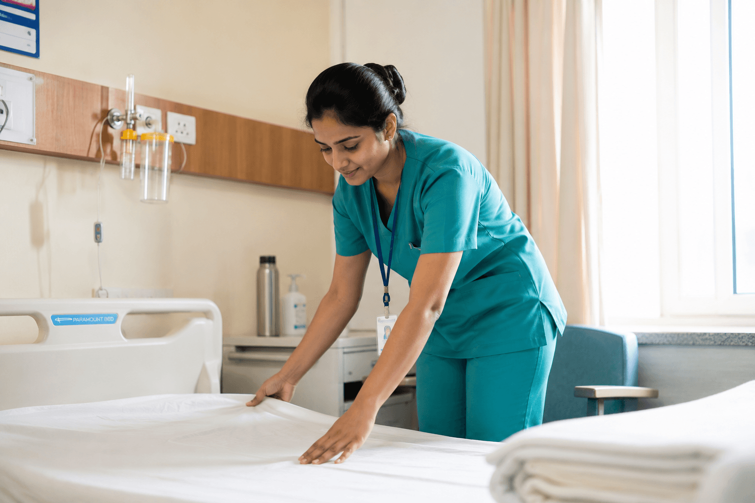 Nurse making up a hospital bed with fresh linen